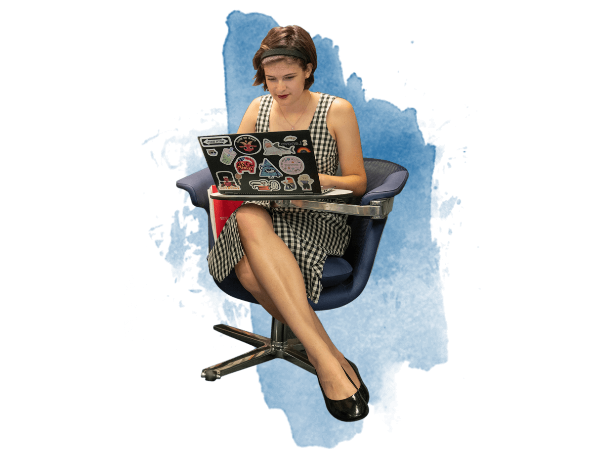 A female student sitting in a chair working on her laptop