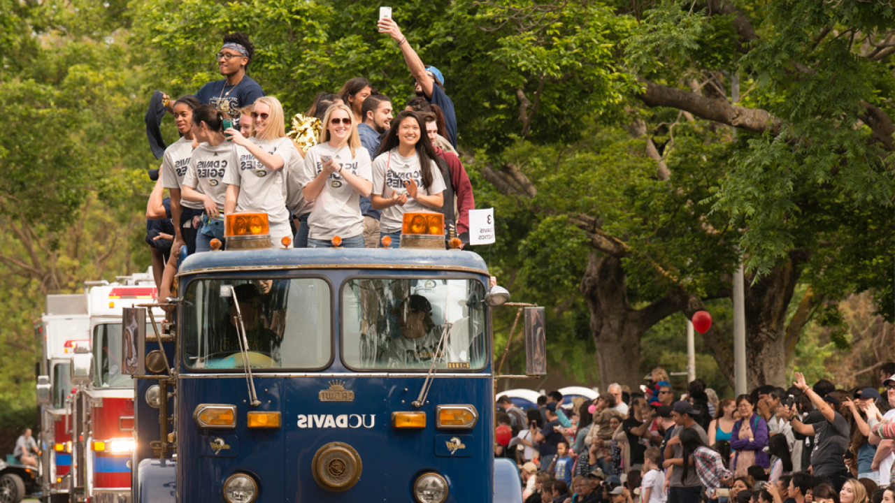 UC Davis students ride on top of a UC Davis branded blue fire engine during the picnic day parade
