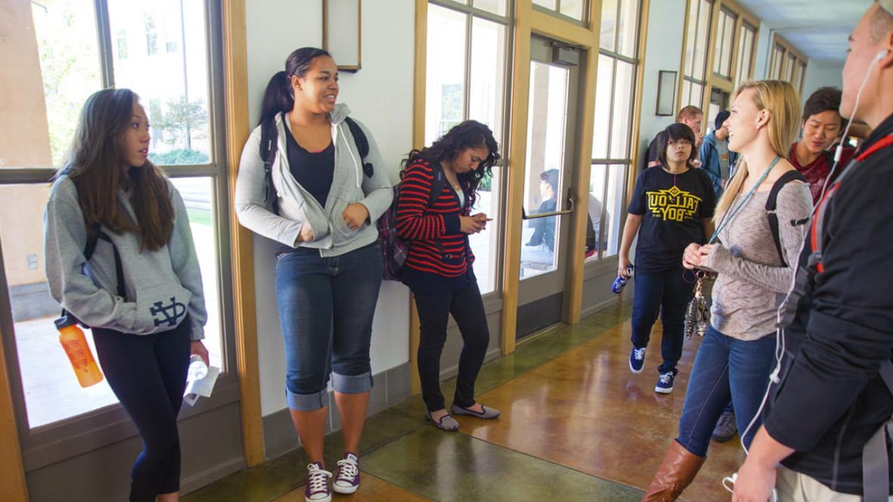 students gathering for a class and chatting in a hallway - transfer application timeline