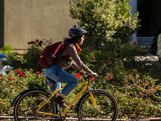 student rides a bicycle while wearing a helmet