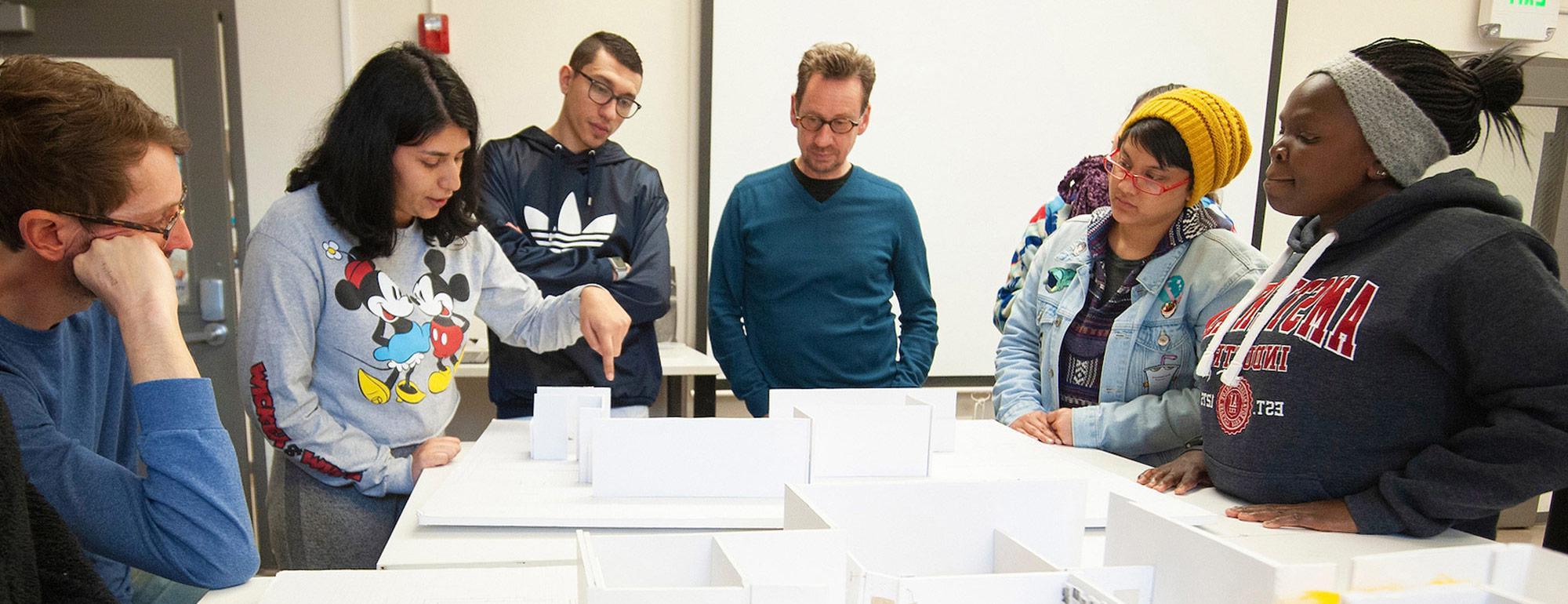 transfer students standing around a model of a building in a design class