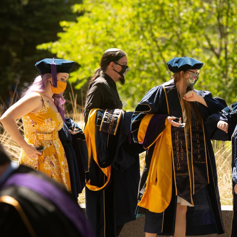students gather in commencement regalia at UC Davis