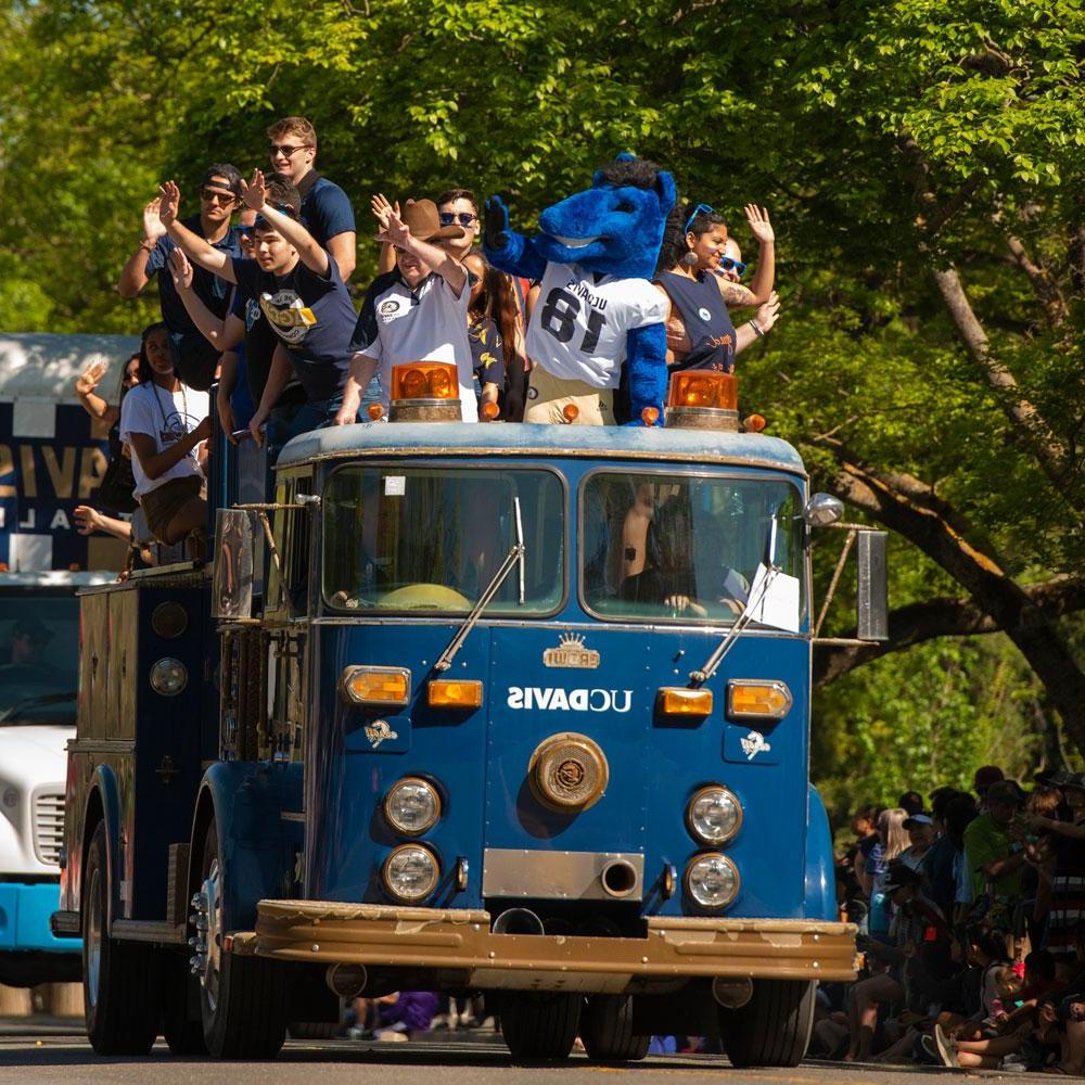 students aboard a truck waving to the crowd during a Picnic Day parade
