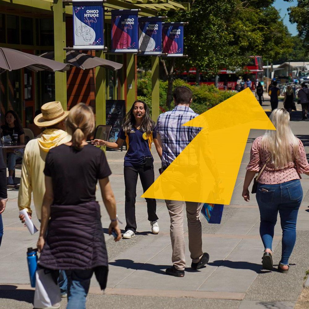A tour group walks through campus with a digital arrow superimposed over them.